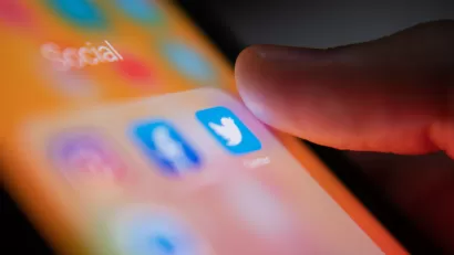 A person’s thumb hovers over the Twitter app on a smart phone.